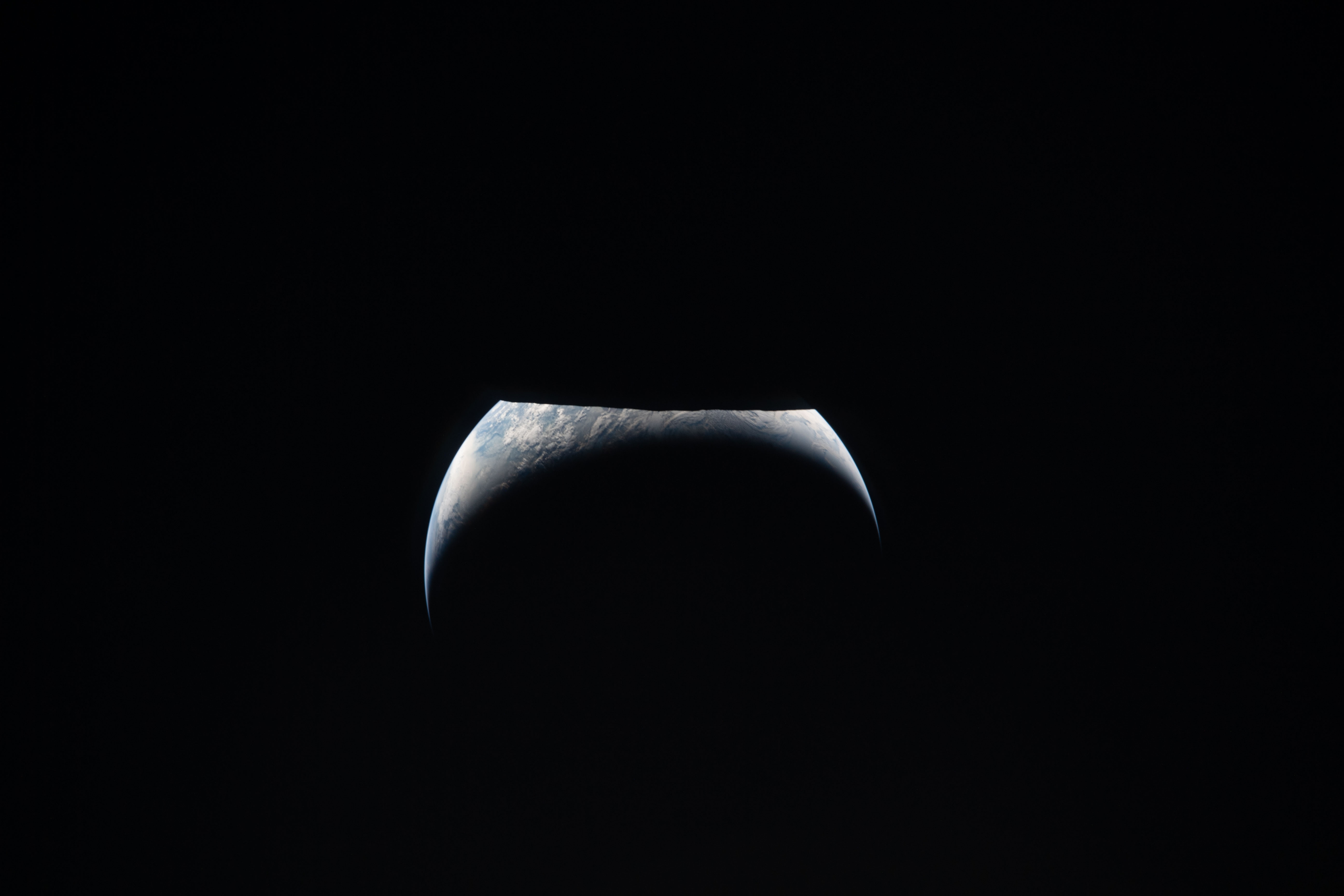 La Tierra parcialmente iluminada aparece junto al borde oscuro de la Luna en una fotografía de Artemis II