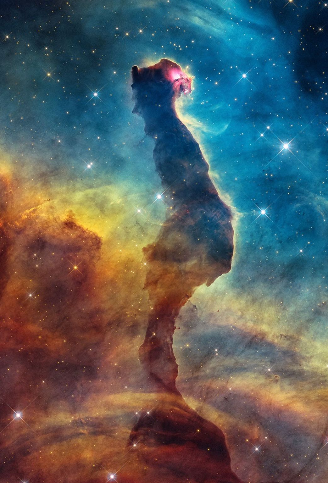 A dark dust pillar in the Cat’s Head Nebula surrounded by glowing gas, observed by Hubble.