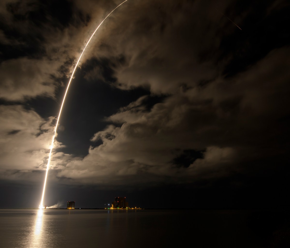A luminous rocket trail from the launch of Lucy in a nighttime long exposure.